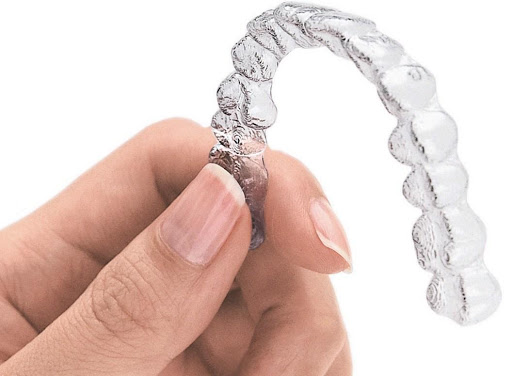 Uma mão segurando um alinhador transparente